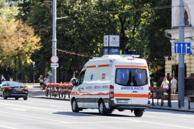 Ambulans minibüsü Chisinau caddesinde hareket ediyor. Ağaçlar ve arabalarla. Moldova başkenti trafiğinde tıbbi yardım aracı.