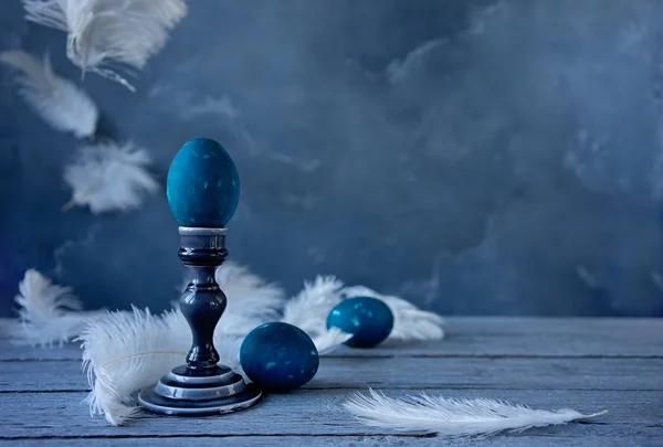 Easter eggs and white feathers on blue background
