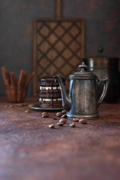 Vintage coffee pot with liquid hot chocolate. Homemade chocolate cake on background