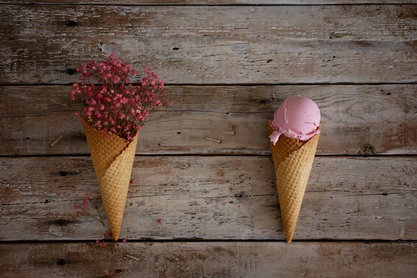 Cremoso helado de frambuesa con bayas de frambuesa y flores de color rosa sobre fondo de madera clara. Vista superior Fotos de stock libres de derechos