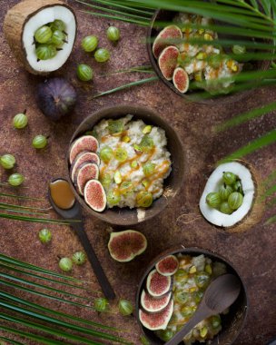 Hindistan cevizi ile yulaf gevreği, Bektaşi üzümü çilek, karamel sos ve koyu arka planda incir dilimleri. Üst görünüm