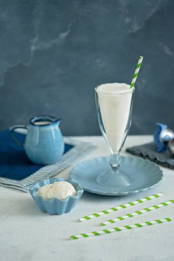 Cam bardakta dondurmamilkshake. Mavi seramik krem kasede dondurma topları. Açık mavi arka plan. Yaz brunch.
