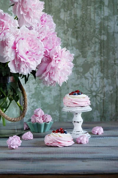 Pavlova cakes with cream and fresh summer berries. Close up of Pavlova dessert on vintage ceramic plate. peonies flowers. Food photography