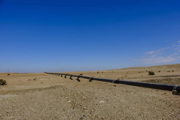 Remote Namib Desert with above ground iron pipe stretching across to carry water from desalination plant in Swakopmund to uranium mine. Built with Chinese investment in belt and road initiative.