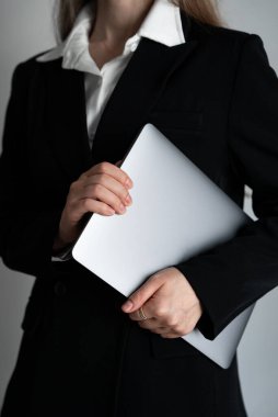 Resmi takım elbiseli bir kadının elinde bilgisayarla çekilmiş dikey fotoğrafı. Modern iş, liderlik ve profesyonellik kavramı. 