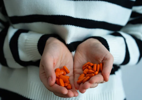 Eller kırmızı kapsülleri tutuyor. İlaç, takviye, vitamin, eczane ve sağlık sembolü. 