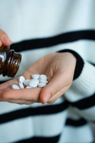 Beyaz hapları şişeden avuç içine döken biri. İlaç, ilaç, tedavi konsepti. 