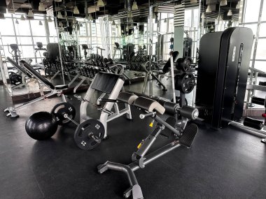 Ağırlık makineleri, bankları ve aynaları olan modern spor salonu. Eğitim, sağlık ve aktif yaşam tarzı temaları için boş fitness kulübü iç mimarisi. 