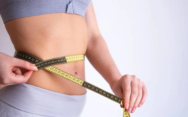 Kadının beline bant saran eller. Zayıflama, diyet, sağlık kontrolü ve vücut ölçümleri kavramı. 