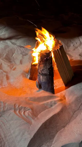 Crackling bonfire on sandy beach at dusk creating a warm glow, Campfire atmosphere, outdoor adventure and evening relaxation.