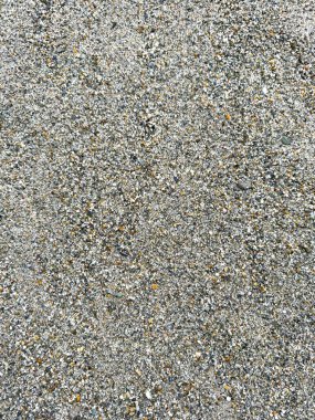 Yüksek çözünürlüklü fotoğraf, arka planda kullanılabilecek dokulu bir yüzey oluşturan küçük taşlar ve kumları gösteriyor..