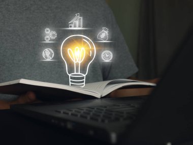 Bir kitaptan parlayan ampul ikonu, yaratıcılığı, bilgiyi, öğrenmeyi ve yeniliği sembolize ediyor. İş ve finans simgeleriyle çevrelenmiş olup, eğitim, araştırma ve yeni fikirleri temsil etmektedir..