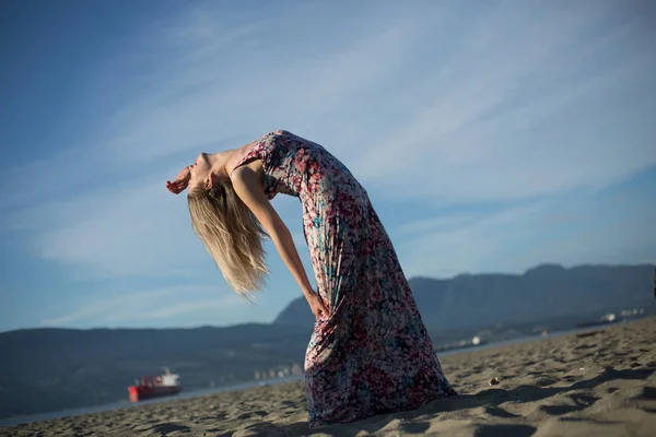 Sarışın genç kadın uzun saçlı streching beach — Stok fotoğraf
