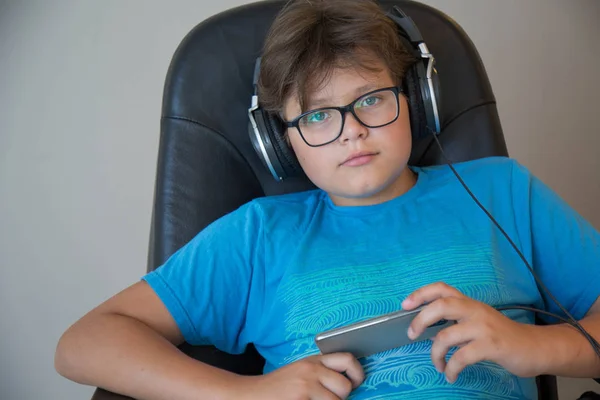 Lindo adolescente chico usando gafas auriculares holdig teléfono celular — Foto de Stock