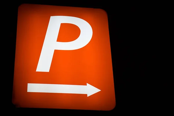 Naranja signo de estacionamiento indicador flecha fondo oscuro espacio de copia de primer plano —  Fotos de Stock