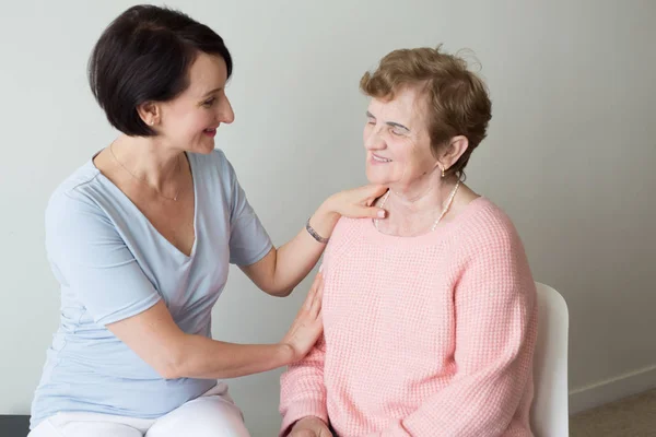 Young female holding hand on shoulder of elderly woman Stock Image