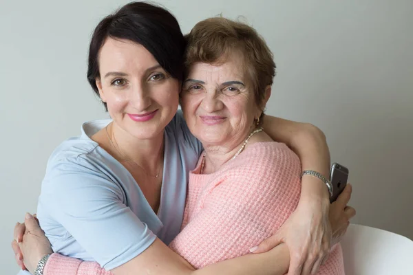 Elderly mother with adult daughter hugging portrait Stock Image