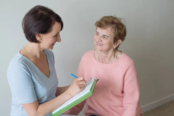 Genç ve yaşlı kadın pano kağıdı yazıyor.