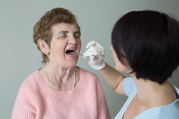 Caregiver kvinnlig medicinsk examen pensionerad kvinna öppen mun Stockbild