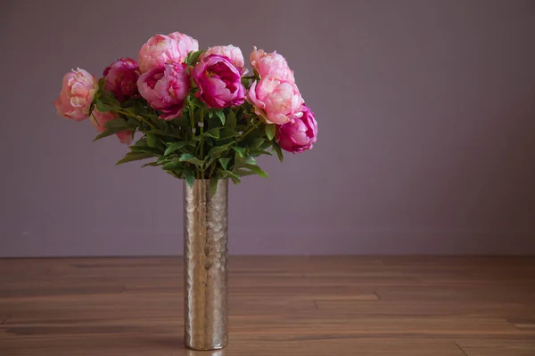 Pioen roze bloemen hoge vaas houten vloer paarse achtergrond — Stockfoto