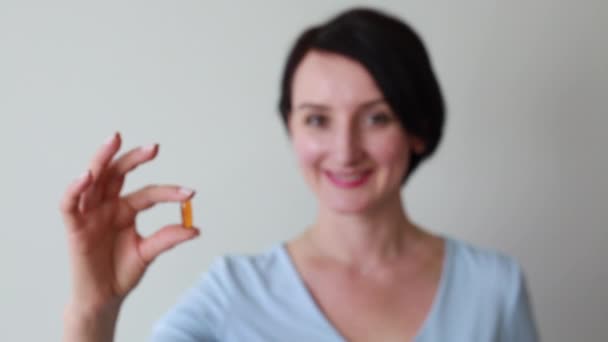 Young smiling female holding pill — Stock Video