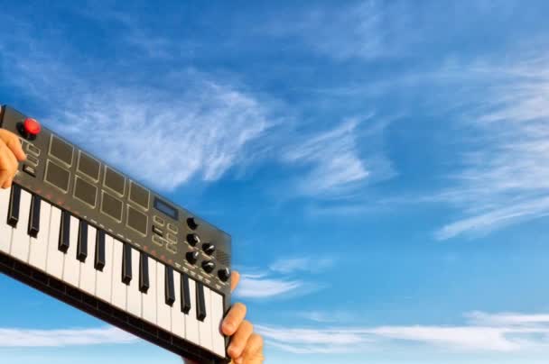 Mani che tengono la musica pianoforte tastiera sfondo cielo zoom — Video Stock