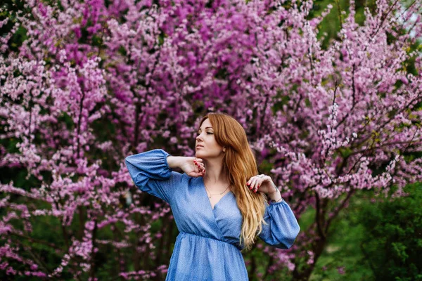 Piękne Dreaming rudowłosy Kobieta w czasie wiosny kwitną cherrytrees ogród. — Zdjęcie stockowe