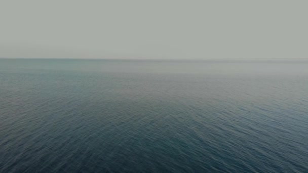 La cámara vuela sobre las borrosas olas del océano hacia el horizonte limpio. Vista aérea . — Vídeos de Stock