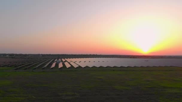 Flygdrönare vy in i stora solpaneler på en solgård vid solnedgången. Solcellsanläggningar. Videofilm 4k. — Stockvideo