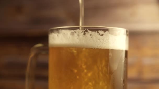 A közelről feltöltött sört egy sörpohárba öntik, fogantyúval, sok buborékkal és habbal, ami lefolyik az üvegen. Meleg fa háttér