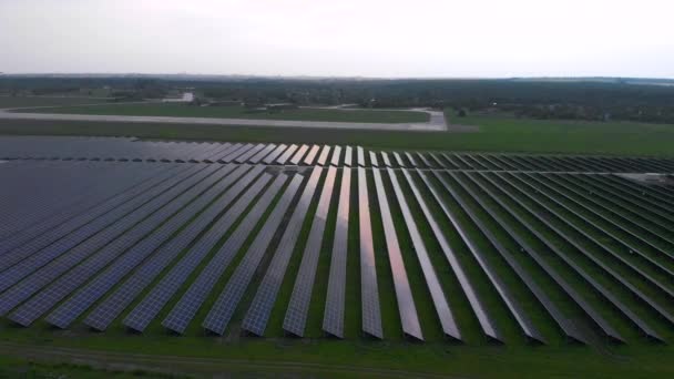 Drone langzaam vliegt in grote zonnepanelen op een zonne-boerderij op bewolkte zomeravond. Zonnecellen, groen gras. Beeldmateriaal video 4k. — Stockvideo