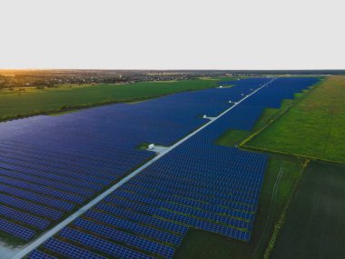 Parlak yaz günbatımında güneş çiftliğindeki büyük güneş panellerinin insansız hava aracı görüntüsü. Güneş pili santralleri, renkli fotoğraf