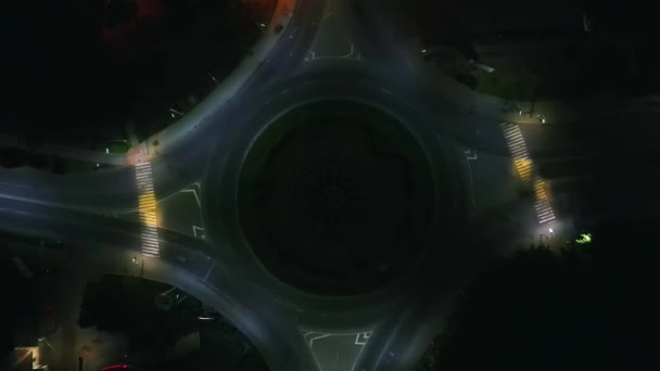 Воздушный обзор круговой дороги с круговыми автомобилями ночью в маленьком европейском городе — стоковое видео