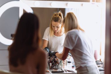 Makyaj sanatçısı, iş yerinde profesyonel güzellik salonu ve yaratıcı sınıflarda genç mankenle iş başında.
