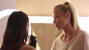 Makyajcı kadın, iş yerinde, profesyonel ve güzel bir modelle çalışıyor. Makyaj sanatçısı küçük bir güzellik salonunda çalışıyor.