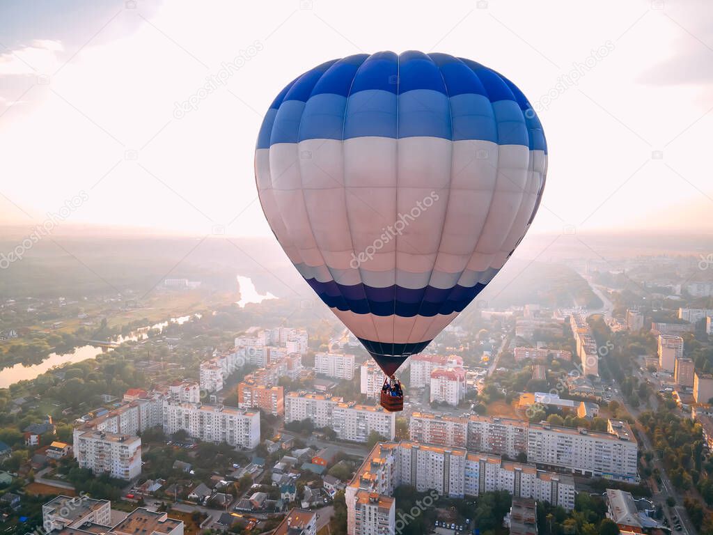 Colorful hot air balloon flying over small european city at summer sunset, Kiev region, Ukraine