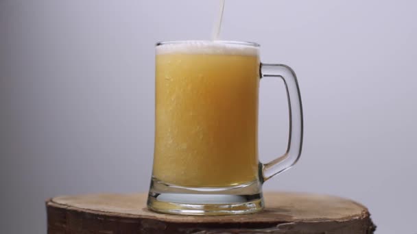 Plan au ralenti de la bière légère est versé dans un verre de bière avec une poignée, beaucoup de bulles et de mousse qui coule dans le verre. — Video