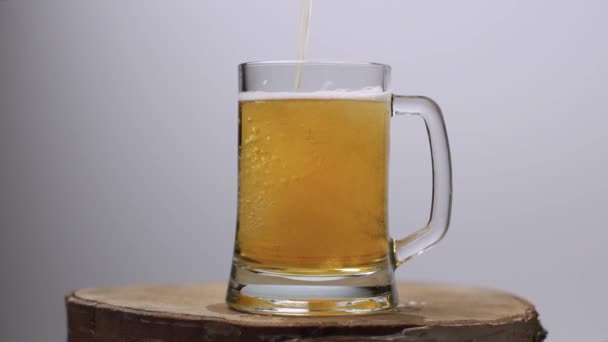 Повільний постріл легкого пива вливається в пивний келих з ручкою, безліч бульбашок і піни — стокове відео
