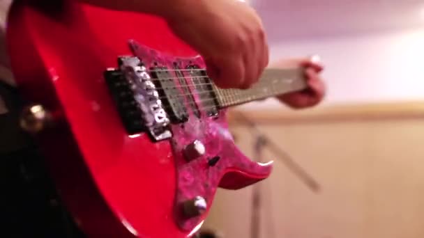 Κοντινό πλάνο των αρσενικών χεριών κιθαρίστα που παίζουν σε κόκκινη ηλεκτρική κιθάρα — Αρχείο Βίντεο