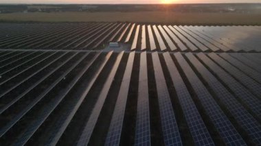 Parlak günbatımında güneş çiftliğindeki büyük güneş panellerine hava aracı görüntüsü. Güneş pili santralleri. görüntüler 4k.