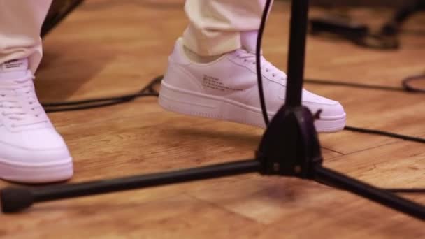Beyaz spor ayakkabılı bir şarkıcı mikrofonun yanında dururken ayaklarıyla dans ederek müzik ritmini düşürür. Yakın çekim eller kamera görüntüsünü sallar. — Stok video