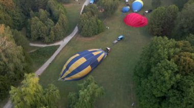 Sıcak hava balonlarının havadan görünüşü küçük Avrupa şehrinde park halinde bir yaz sabahı için hazırlanıyor.