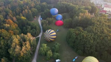 Sıcak hava balonlarının havadan görünüşü küçük Avrupa şehrinde park halinde bir yaz sabahı için hazırlanıyor.