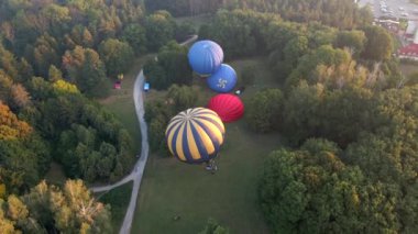 Sıcak hava balonlarının havadan görünüşü küçük Avrupa şehrinde park halinde bir yaz sabahı için hazırlanıyor.
