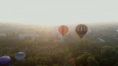 Avrupa 'nın küçük bir şehrinde yaz gündoğumunda yeşil park ve nehir üzerinde uçan iki renkli balon.