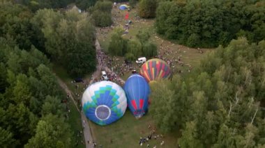Bir sürü insan sıcak hava balonlarının küçük Avrupa şehrinde park halinde bir yaz akşamına nasıl hazırlandığına bakıyor. Hava 4k görünümü.