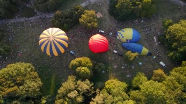Birçok insan sıcak hava balonlarının küçük bir Avrupa şehrinde park halinde bir yaz akşamına nasıl hazırlandığına bakıyor.