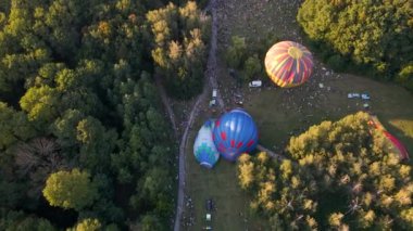 Birçok insan sıcak hava balonlarının küçük bir Avrupa şehrinde park halinde bir yaz akşamına nasıl hazırlandığına bakıyor.