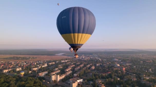 Balões de ar quente coloridos voando sobre o parque verde em pequena cidade europeia no nascer do sol de verão, vista aérea — Vídeo de Stock