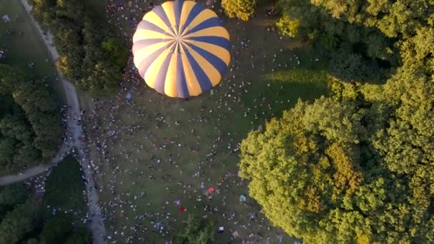 Eine Menge Leute sehen zu, wie sich Heißluftballons auf einen Sommerabend vorbereiten, der im Park in einer kleinen europäischen Stadt fliegt, Luftaufnahmen in 4k — Stockvideo